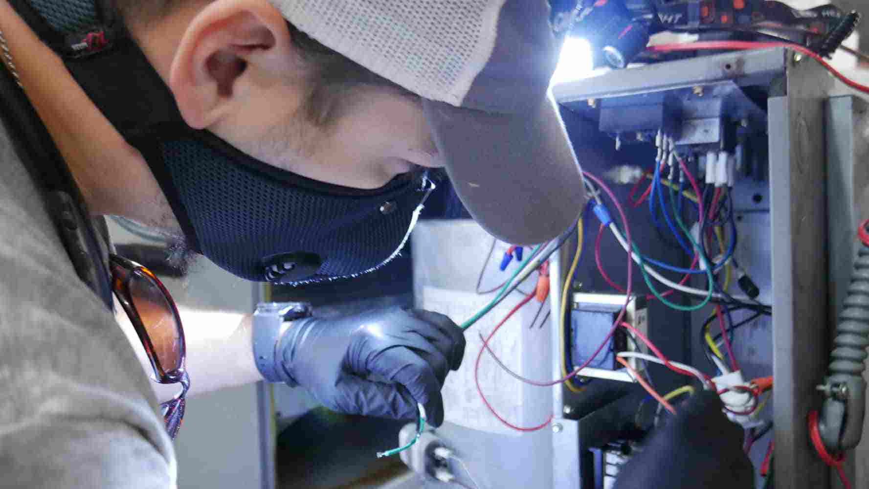 Un technicien chauffagiste bricole avec les fils du chauffage